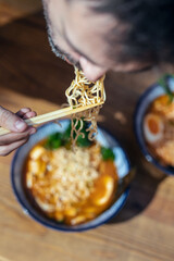 Handsome mature man eating ramen with chopsticks in an asian restaurant