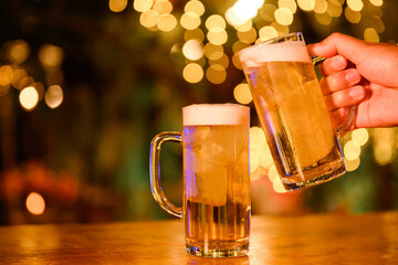 Close-up of two male friends drinking beer happily Clink a glass of beer in the pub Beautiful background of bokeh. Soft focus, shallow DOF.