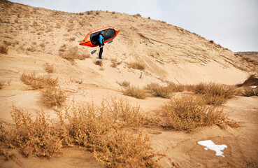Man with orange raft boat at sand dune