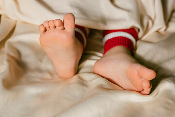 Children's feet on a white bed. Infant baby is sleeping in his crib for holidays. Importance of sleep for babies. Sleep mode babies 3 y.o.