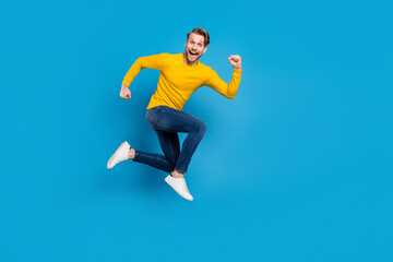Obraz premium Full length side profile body size photo of young man jumping high running fast isolated vivid blue color background