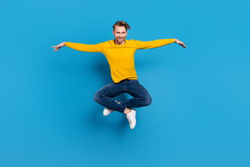 Full length body size of young guy jumping up cheerful funny childish playful isolated bright blue color background