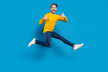 Fototapeta na wymiar Full length body size of young guy smiling jumping up showing like gesturing isolated vibrant blue color background