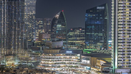 Shopping mall exterior with reataurants near fountain in Dubai downtown aerial night timelapse, United Arab Emirates
