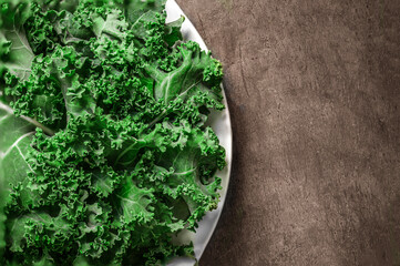 Kale leaf salad vegetable on wooden background. Kale closeup on a plate. Flat lay. Food  vegan concept..