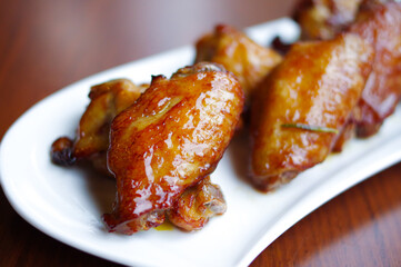 roasted honey buffalo chicken wings and legs with dipping sauce and celery on white plate