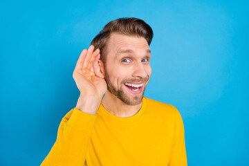 Photo portrait of man listening rumor keeping hand near ear isolated on vibrant blue color background