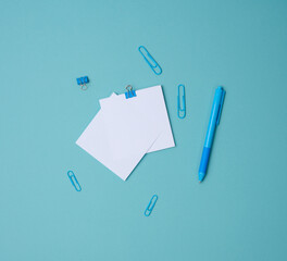 stack of white square sheets of paper for notes, stationery on blue background, top view