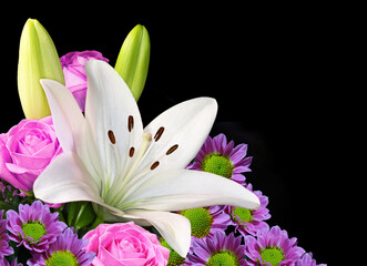 A bouquet of flowers with Easter lily roses and daisies in closeup on a black background