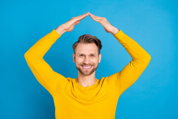Photo of young guy happy positive smile show hands roof home real estate isolated over blue color...