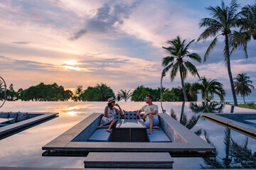 couple watching the sunset in an infinity pool on a luxury vacation in, man and woman watching the...