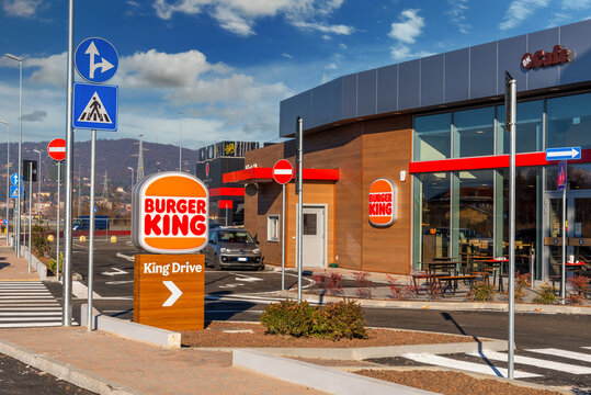 Moncalieri, Turin, Italy - December 6, 2021: King Drive of New Burger King Restaurant with in via Fortunato Postiglione, sign post with new logo on blue sky with clouds