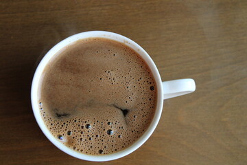 Cup of coffee on a wooden background, top view