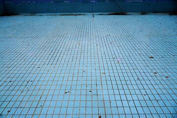 Schwimmbecken mit blauen Kacheln ohne Wasser im Schwimmbad im Herbst