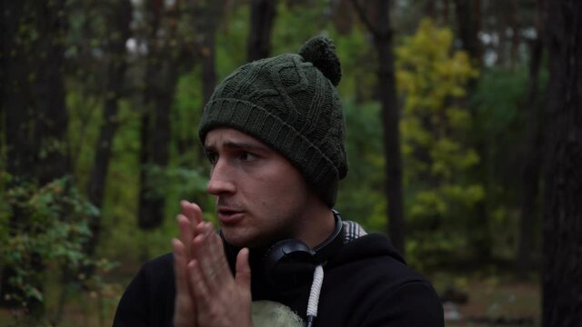 a man notices in the forest in headphones and a hat