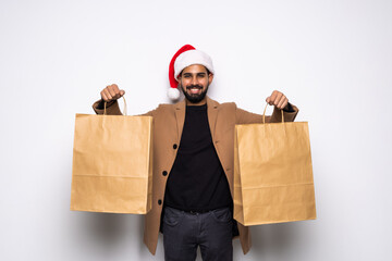 pleased man in santa hat holding shopping bags while looking away on white background