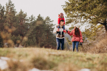 Obraz premium Young family together walking in forest at winter time