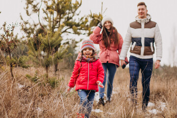 Young family together walking in forest at winter time