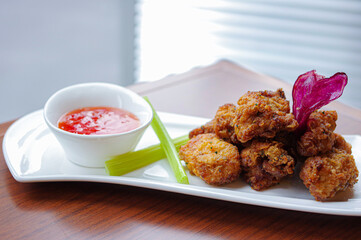 karaage japanese fried chicken nuggets and celery on white plate with sweet and sour sauce