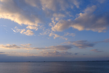 明け方の冬の海。太陽が昇り雲の間から顔を出し、水面はキラキラと輝く。兵庫県芦屋市芦屋浜で撮影。