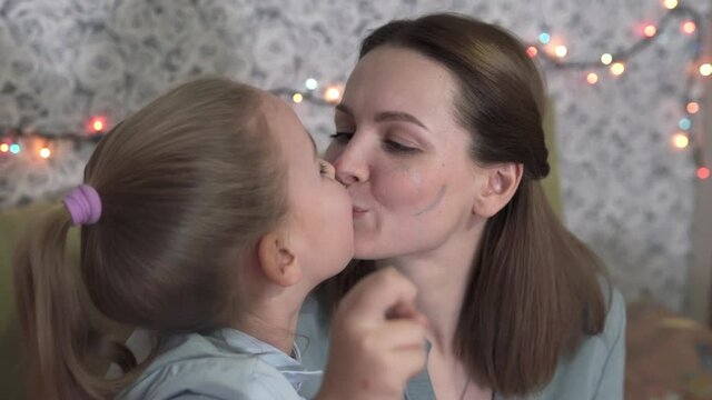 Mom and daughter hug and kiss in New Year's mood. On Christmas and New Years, the family spends time at home together.