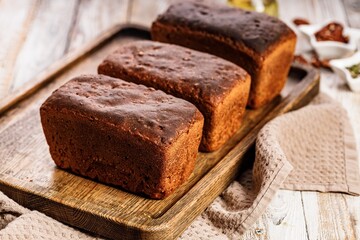 Organic rye bread loafs. Fresh bread made from whole grain rye flour. Homemade delicious pastries on a wooden tray on a rustic background. Close-up. Copy space