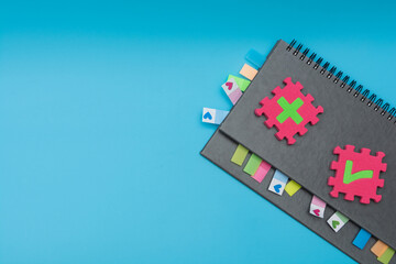 Gray weekly planner with bookmarks and puzzles with symbols on a blue background. The concept of planning and solving complex problems for the development of business and personality