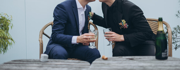Fototapeta premium European Gay Couple having a glass of champagne, nice beginning of a wedding day, same sex couple marriage.