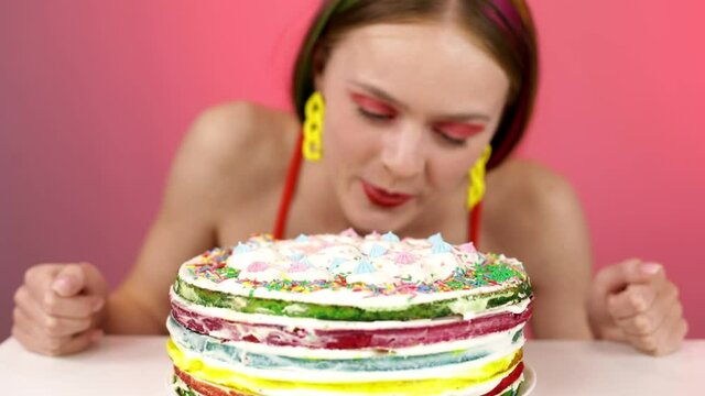 A young girl licks a big birthday cake.