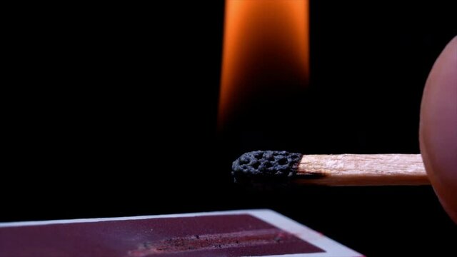 4k Video Slow motion cinematic macro shot of a match being lit, in a dark room.