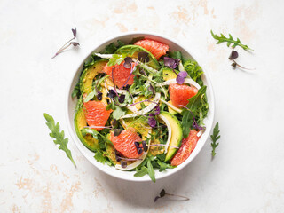 Grapefruit, avocado, arugula, sprouts and fennel salad in white bowl.