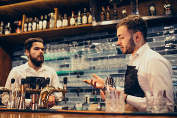 Handsome bartender making drinking and cocktails at a counter