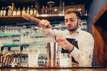 Handsome bartender making drinking and cocktails at a counter