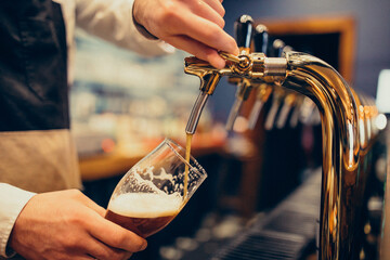 Male bartender pouring beer at a pub