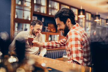 Two handsome bearded man drinking beer in pub