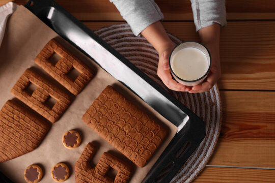 Little Child Holding Glass Of Milk Near Baking Sheet With Christmas Pastry At Wooden Table, Top View