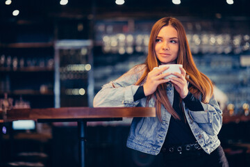 Young beautiful woman drinking coffee in bar