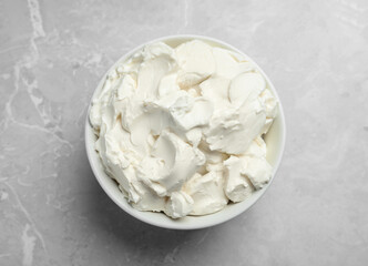 Bowl of tasty cream cheese on light grey marble table, top view
