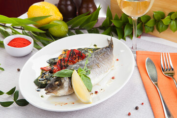 Baked pikeperch and vegetables on a white plate, and a glass of white wine.