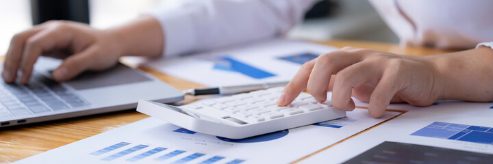 Fototapeta premium accounting concept, Businesswoman using a calculator with computer laptop, budget, and loan paper in the office.