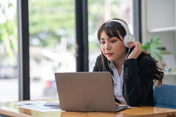 Portrait of a business woman happily wearing music headphones while working to relax after a hard day's work.
