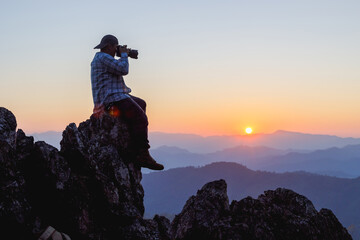 Professional Nature Photographer taking photos on top mountains sunset background. Nature Photography Concept.