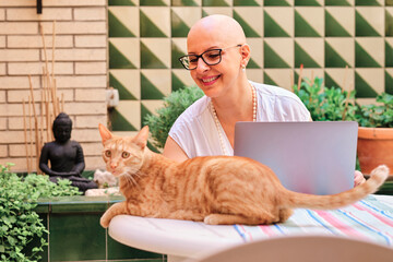 Mature woman with cancer looking at cat while sitting in backyard