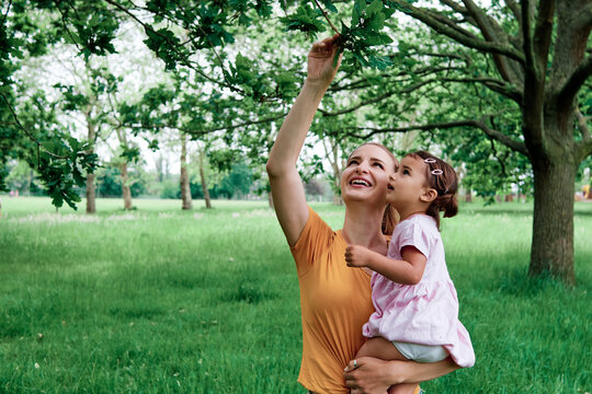 Mother showing leaves to daughter at park