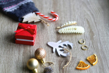 Wool stocking with small presents and Christmas decorations on wooden background. Selective focus.