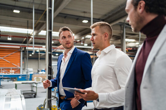 Male inspector holding digital tablet while discussing with businessmen at industry