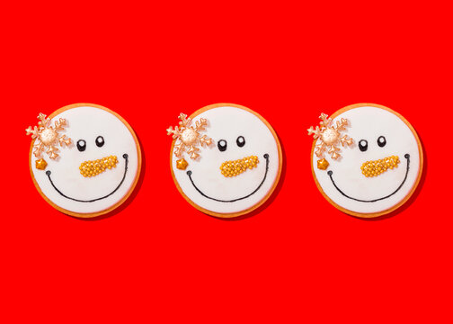 Three snowman shaped Christmas cookies against vibrant red background