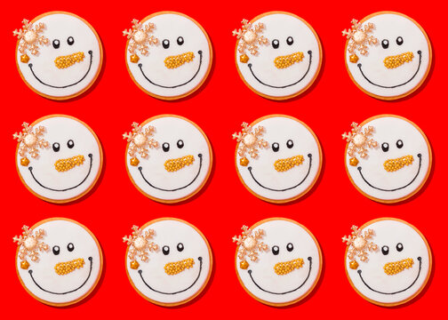 Pattern of snowman shaped Christmas cookies flat laid against vibrant red background