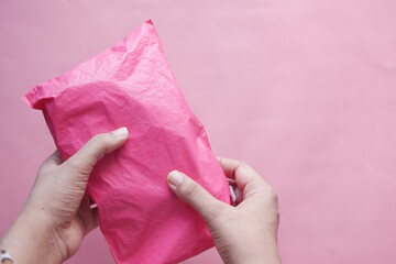 holding pink color paper bubble envelope on table 