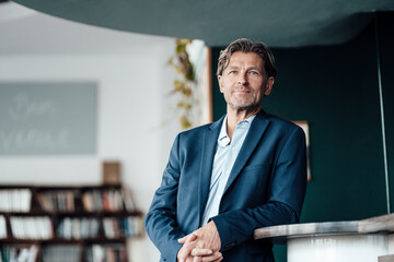 Businessman with hands clasped leaning on table in cafe